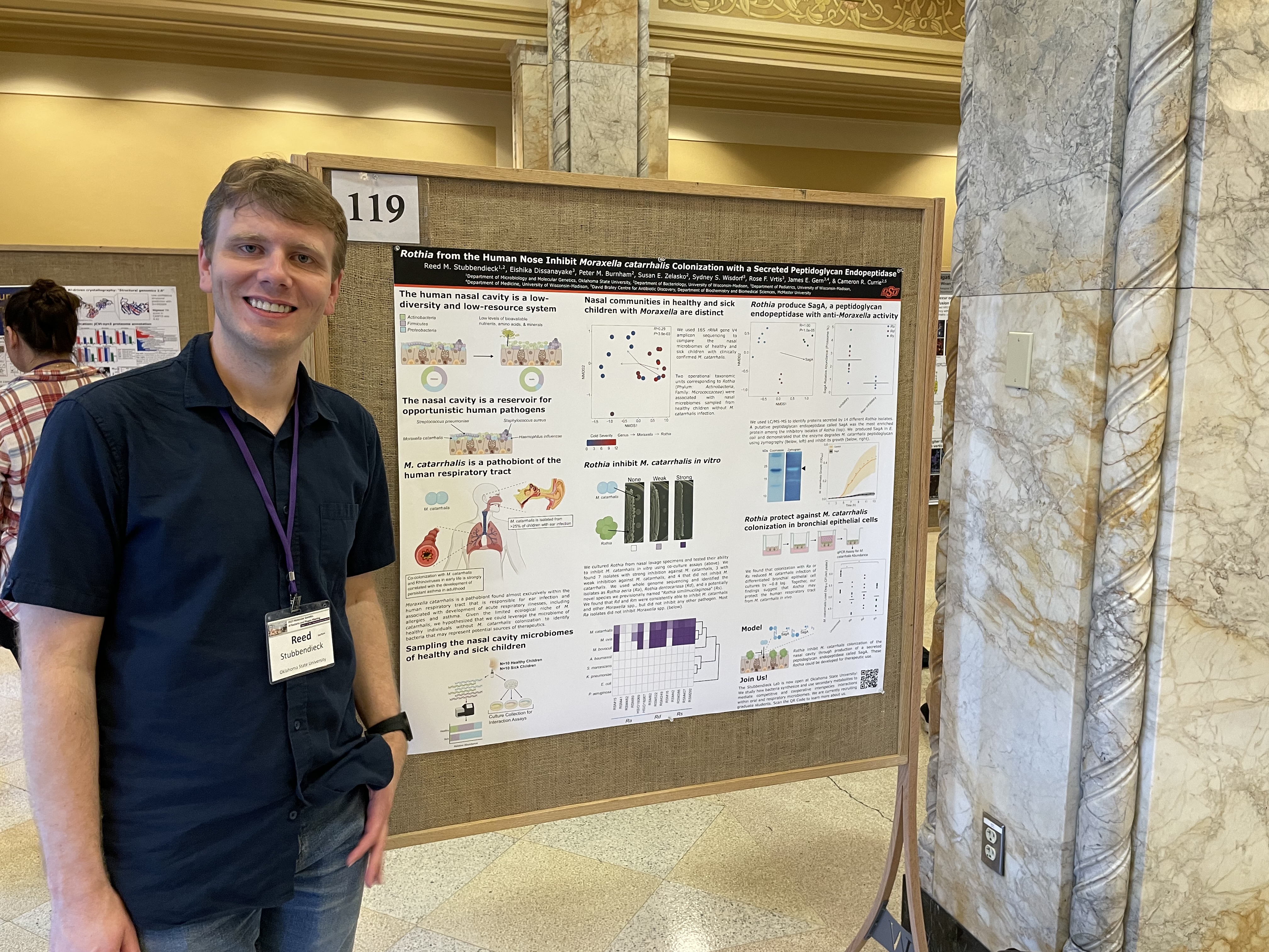 Photograph of Reed standing in front of a poster at the 2023 Phages meeting.